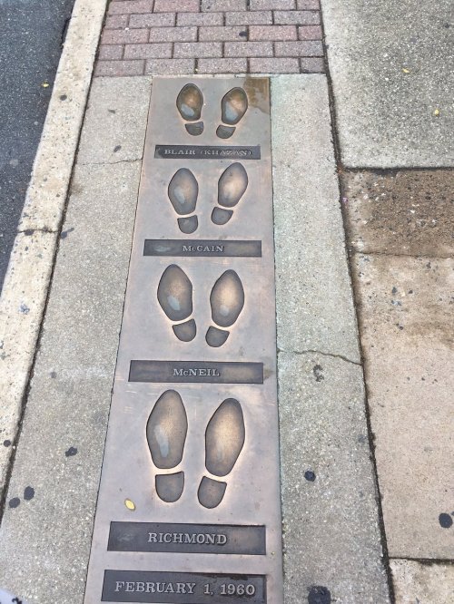 Bronze footprints embedded in pavement, honoring Blair, McCain, McNeil, and Richmond, dated February 1, 1960.