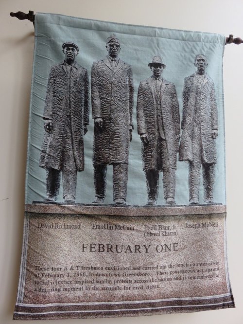 A banner featuring four historical figures in suits, commemorating their role in the civil rights movement on February 1.