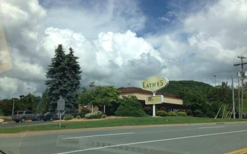 A restaurant named "Kathy's" with a large sign, surrounded by trees and a cloudy sky.