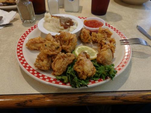 A plate of fried chicken with a side of mashed potatoes and gravy, garnished with lemon and lettuce.