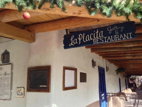 Sign for "La Placita Gallery & Restaurant" under a wooden awning, with festive decorations above.