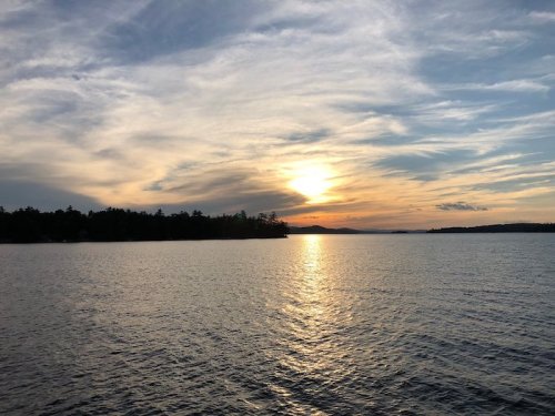 A serene sunset over a calm lake, with colorful clouds reflecting on the water's surface.