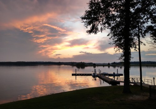 A serene lake at sunset, with colorful clouds reflecting on the water and a dock extending into the scene.