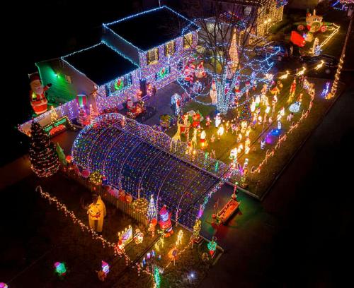 A festive house decorated with colorful Christmas lights, inflatables, and holiday decorations in a vibrant display.