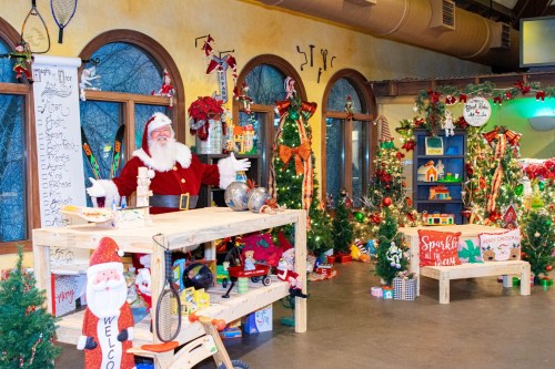 A festive room decorated for Christmas, featuring Santa, trees, toys, and colorful holiday decorations.