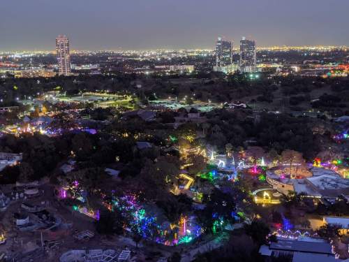 Aerial view of a cityscape at night, featuring colorful lights in a park and buildings in the background.