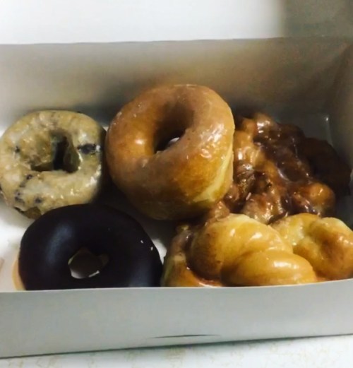A box of assorted donuts, including glazed, chocolate, and a twisted variety.