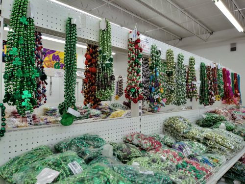 A display of colorful beaded necklaces and decorations in various shades of green, red, and purple on shelves.