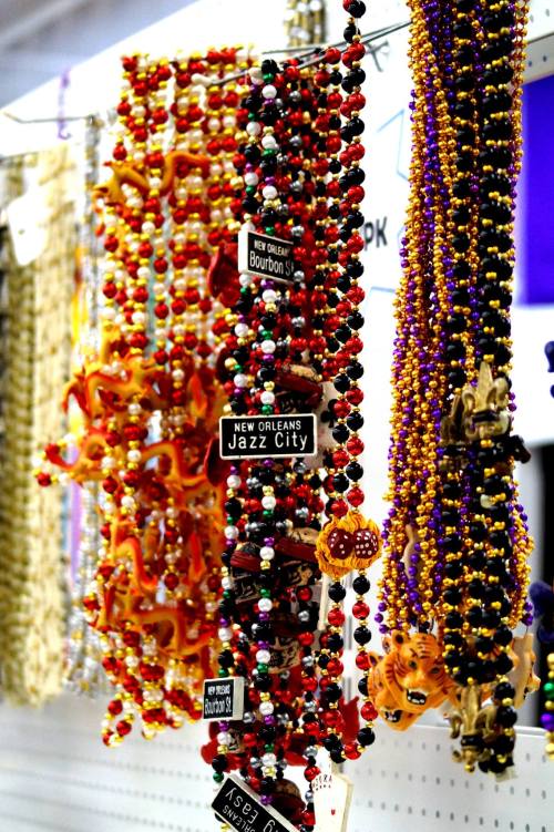 Colorful Mardi Gras beads in various styles, featuring signs for "Bourbon St" and "Jazz City."