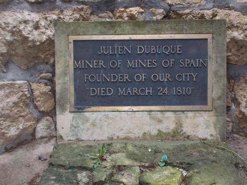 Plaque honoring Julien Dubuque, miner and founder of the city, died March 24, 1810. Set against a stone wall.