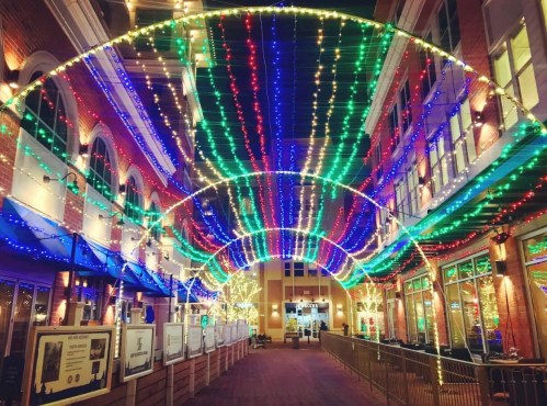 A vibrant alleyway adorned with colorful string lights in blue, green, and red, creating a festive atmosphere at night.