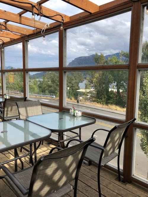 A cozy dining area with glass walls, overlooking a scenic view of mountains and trees.