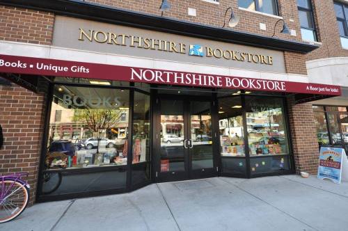 Exterior of Northshire Bookstore featuring large glass windows and a red awning, showcasing books and gifts.