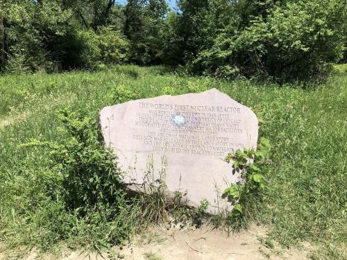 A large stone marker in a grassy area, commemorating the site of the world's first nuclear reactor.