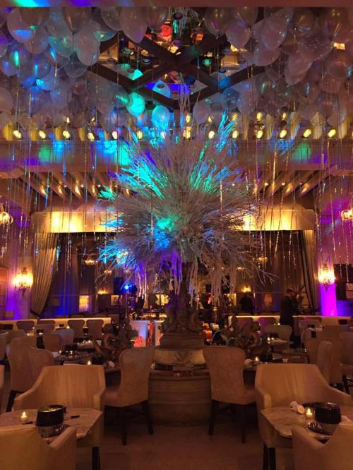 A vibrant restaurant interior with colorful lighting, balloons, and a large decorative centerpiece.