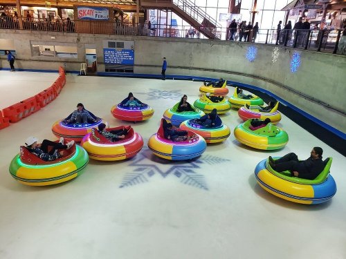 A group of people enjoying bumper cars on an ice rink, surrounded by colorful inflatable vehicles.
