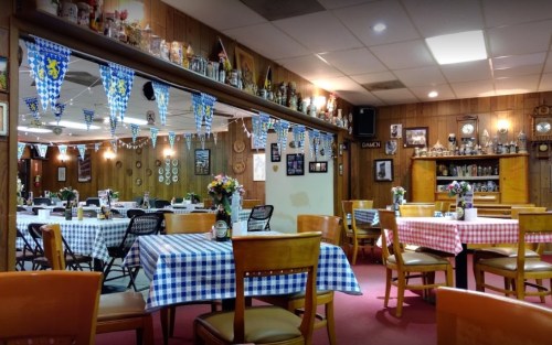 Cozy restaurant interior with checkered tablecloths, wooden walls, and festive decorations.