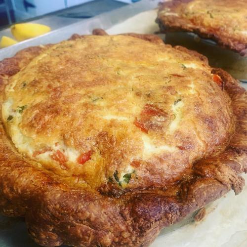 Two golden-brown savory pies with a flaky crust, filled with vegetables, on a baking tray.