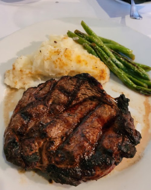 A grilled steak served with mashed potatoes and steamed asparagus on a white plate.