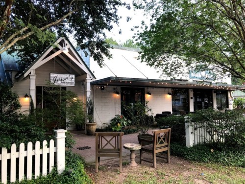 Exterior of Jesse's Restaurant, featuring a white building, outdoor seating, and lush greenery.