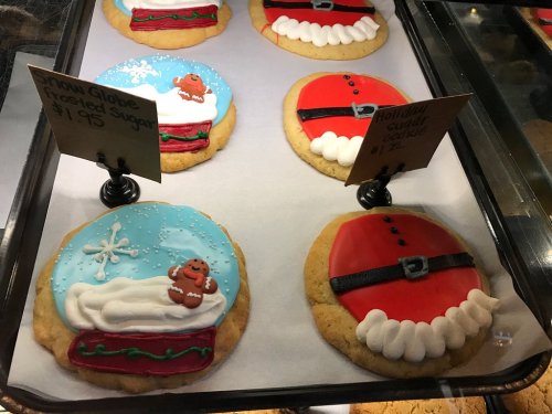 Two festive cookies: one decorated as a snow globe with a gingerbread man, the other resembling Santa's suit.