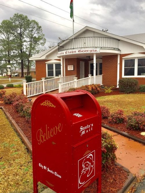 A red mailbox labeled "Santa's Mail" in front of a brick building with a sign reading "Santa Claus Georgia."