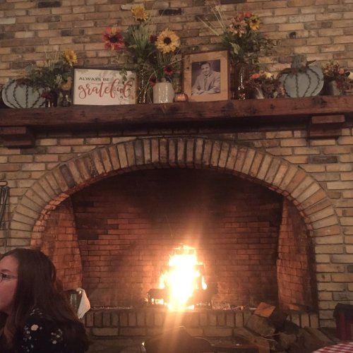 Cozy fireplace with a brick arch, decorated with flowers and a photo, creating a warm, inviting atmosphere.