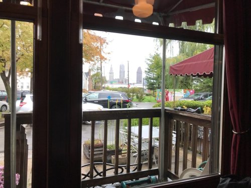 View from a window showing a rainy street scene with cars and distant city buildings.