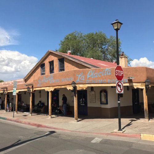 A southwestern-style building with "La Placita" signage, featuring a stop sign and people sitting outside.