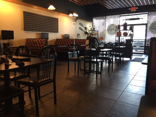 Interior of a restaurant featuring dark wooden tables, leather booths, and a welcoming atmosphere.