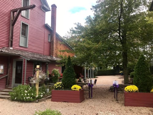 A charming outdoor area with flower planters, trees, and a rustic building in a serene setting.