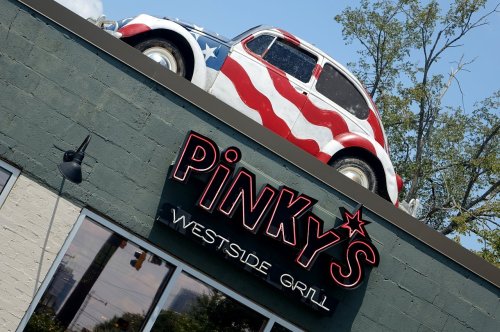 A vintage car painted with an American flag design sits atop the Pinky's Westside Grill building.