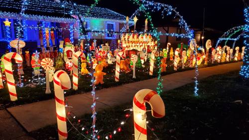 A festive display of colorful holiday decorations, including candy canes and various illuminated characters, at night.