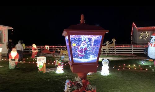 A festive scene featuring a lamp post with a snow globe depicting Santa, surrounded by holiday decorations and lights.
