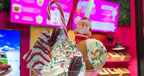 A festive ice cream sundae topped with whipped cream, candy canes, cookies, and colorful sprinkles in a vibrant setting.