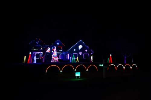 A house decorated with colorful Christmas lights, featuring a Santa figure and illuminated decorations in the yard.