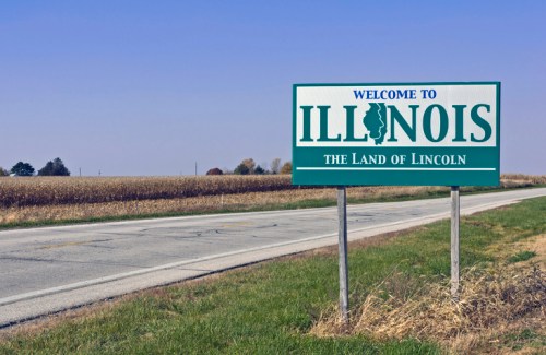 Welcome sign for Illinois, featuring "The Land of Lincoln," with a cornfield in the background and a clear blue sky.