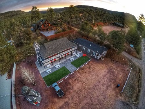 Aerial view of a rustic property with two buildings, surrounded by trees and gravel paths, in a rural setting.