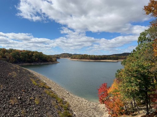 A serene lake surrounded by colorful autumn trees under a partly cloudy sky.