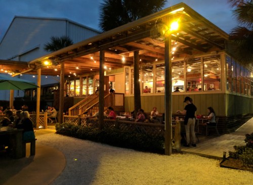 A cozy restaurant with outdoor seating, warm lights, and diners enjoying their meals in a relaxed atmosphere.