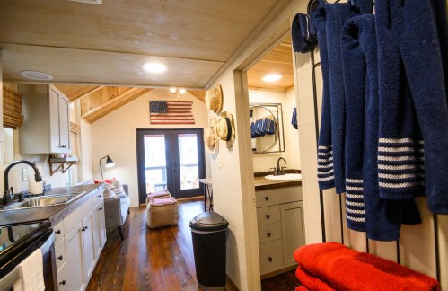 Cozy interior of a small home featuring a kitchen, bathroom, and decorative elements like an American flag and towels.