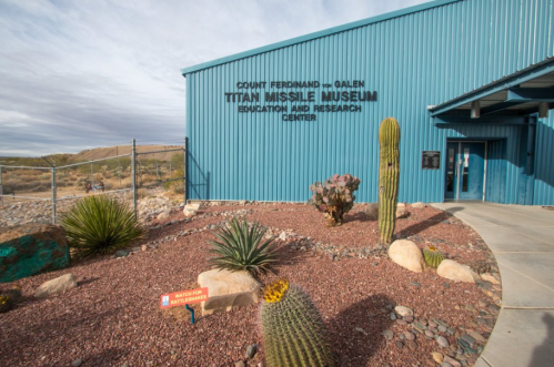 Exterior of the Titan Missile Museum, featuring a blue building, desert landscaping, and a sign for the museum.