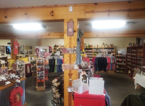 Interior of a cozy store featuring shelves of local products, snacks, and merchandise, with wooden beams and warm lighting.