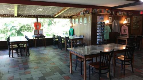 Interior of a cozy restaurant with wooden tables, chairs, and a display of shirts and artwork on the walls.