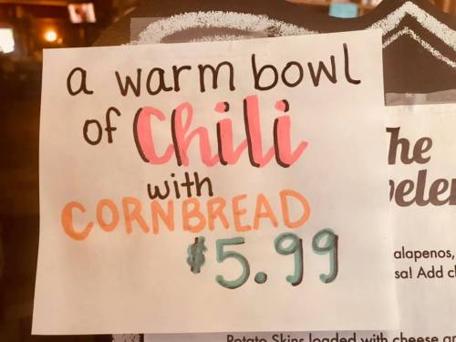 Sign advertising a warm bowl of chili with cornbread for $5.99, featuring colorful handwritten text.