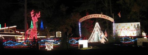 A festive display of colorful Christmas lights, featuring a reindeer, a tree, and a "Merry Christmas" sign at night.