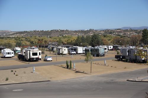 A wide view of an RV park with several parked RVs and a clear blue sky in the background.