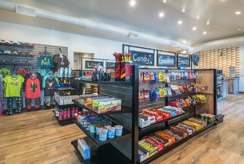 A brightly lit store interior featuring shelves stocked with snacks, candy, and merchandise like clothing and accessories.