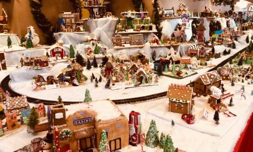 A festive display of intricately decorated gingerbread houses and snowy landscapes, complete with miniature trees and trains.