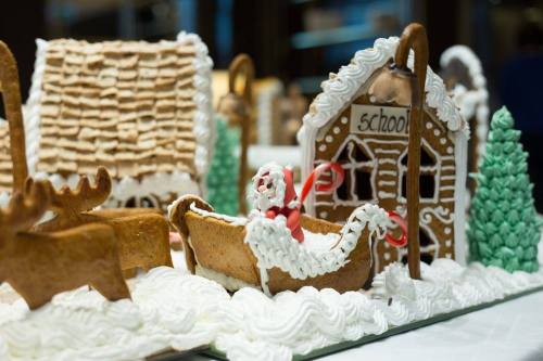 Gingerbread scene featuring a sleigh with Santa, a schoolhouse, and decorated trees, all surrounded by icing.